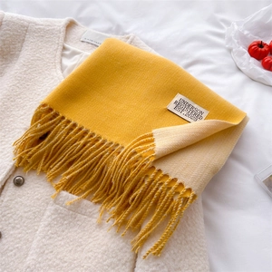 Detail of yellow and beige cashmere-like scarf with fringe and sewn-on woven label