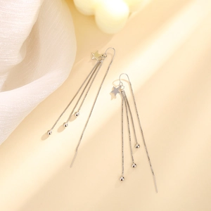 Macro detail of silver star drop earrings with long tassel chains and bead accents