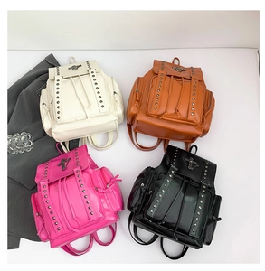 Flat lay of backpacks in four colors featuring metallic cross studs and drawstring closure
