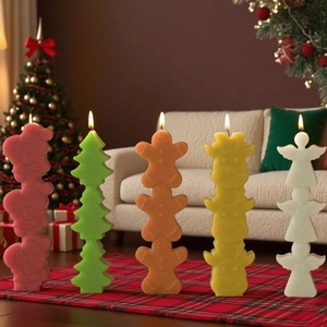 Detailed view of colorful stackable Christmas candle set lit on red plaid rug background