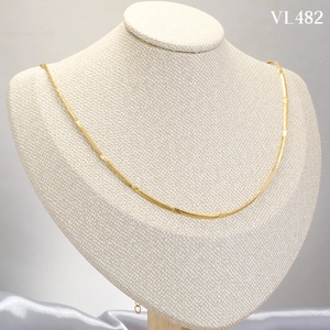 Elegant gold flat snake bone necklace with textured circular discs on a display stand