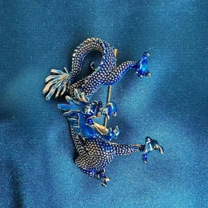 Nahaufnahme der blauen Emaille Drachenbrosche mit silbernen Schuppen auf Seide