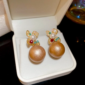 Makroansicht goldener Schmetterlings-Ohrringe mit Strass und Champagner-Perlenanhänger