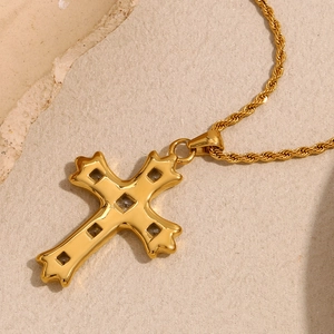 Detail of 18K gold plated cross pendant necklace with clear zircon stone on stone background