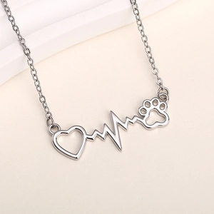 Detailed close-up of a silver heartbeat necklace with heart and paw print pendant charms