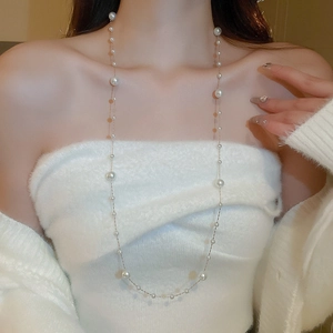 Detail shot of a long pearl tassel necklace featuring varied white pearls and thin gold chain