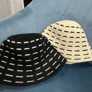 Detailed knit texture of black and beige striped wool bucket hats on blue sofa