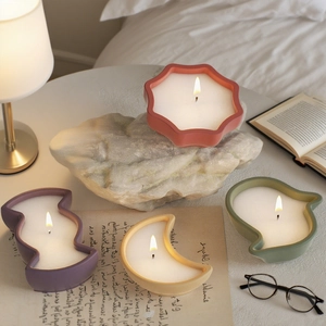 Detailed view of four colorful ceramic scented candles in moon and star shapes on a desk