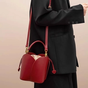 Red petal bucket bag with gold hardware and adjustable strap on a black blazer