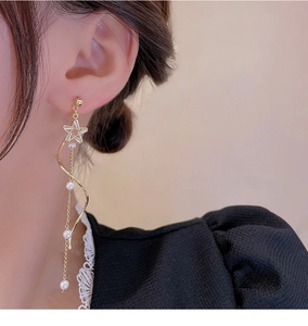 Detail of gold star tassel earrings with white pearls on model showing elegant drape