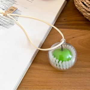 Detailed view of a green apple-shaped ornament inside a clear glass sphere on wooden table