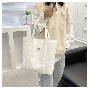 Close-up of white corduroy tote bag with square patch and durable shoulder straps