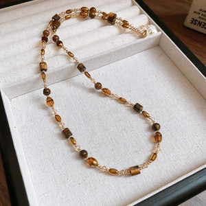 Detail of 18K gold plated tiger eye beaded necklace on beige velvet display case
