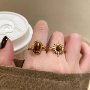 Detail of vintage gold rings set with brown tiger eye stones on hand in a fall scene
