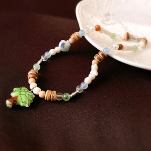 Detail of green ceramic tree pendant with natural wood beads and silver extension chain