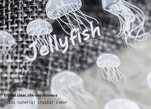 Macro shot of thin jellyfish pattern nail decals with clear glass-like finish on grey fabric