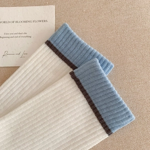 Détail de chaussettes en coton côtelé avec revers bleu clair et rayures sur fond crème
