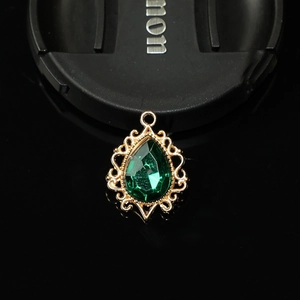 Vue macro d'un pendentif goutte en filigrane doré serti d'une grande pierre verte