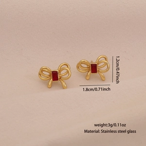 Vue détaillée des boucles d'oreilles nœud dorées avec verre rouge, 1,8cm x 1,2cm