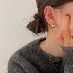 Polished gold ball earrings and twisted rope ring styled with a gray knit sweater