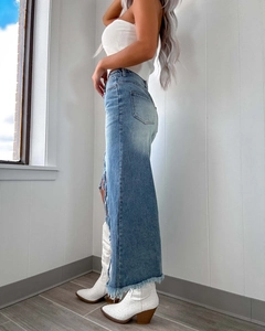 Détail d'une jupe en jean avec fente latérale haute et ourlet effiloché sur le mannequin