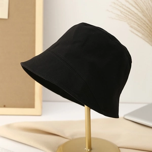 Minimalist black cotton bucket hat showcased on a premium gold metal display stand