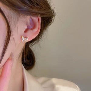 Elegant gold butterfly chain tassel earrings with zircon stones worn by a model