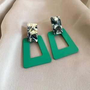 Detail of geometric resin earrings with marble texture on elegant champagne silk fabric