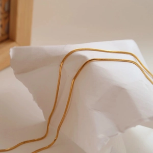 Detailed view of the sleek gold snake chain necklace with a smooth metallic texture