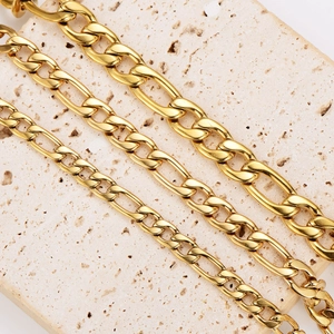 Three gold stainless steel Figaro bracelets in various widths on a stone background