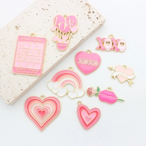 Close-up of pink enamel charms including XOXO and love puzzle heart pendants for DIY jewelry