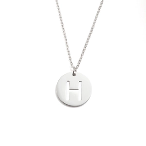 Détail macro du collier en acier inoxydable argenté avec pendentif cercle lettre H