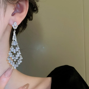Close-up of model wearing silver tassel earrings with geometric cubic zirconia drops