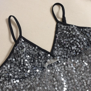 Détail d'un haut à paillettes avec disques argentés et bordures noires fines