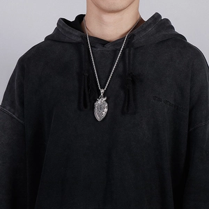 Close-up of vintage silver shield pendant with cross motif on a braided chain necklace