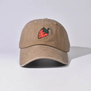 Dettaglio del ricamo a fragola su cappello in cotone lavato kaki con texture vintage