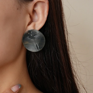 Gros plan de grandes boucles d'oreilles rondes en acrylique à texture marbrée grise et noire