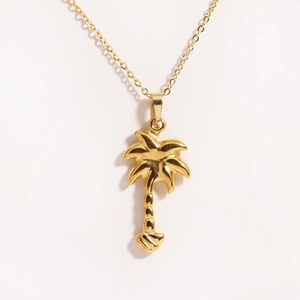 Close-up of polished gold coconut tree pendant with fine chain in minimalist style