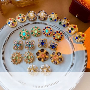 Close-up of vintage gold plated floral earrings with crystals and pearls on a white plate