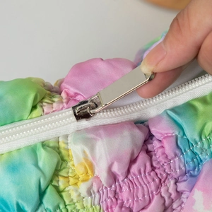 Detailansicht eines silbernen Metallreißverschlusses an einer bunten Tie-Dye-Kosmetiktasche