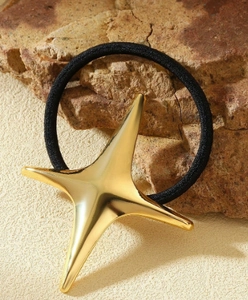 Macro detail of golden star metal pendant on elastic hair tie over textured stone background