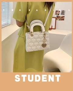 Elegant white heart-shaped quilted handbag with gold heart charm detail on model