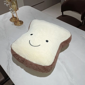 Close-up of soft toast plush pillow with embroidered smile on white marble surface