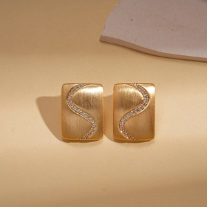 Detail of 18K gold plated square earrings with S-curve zircon inlays and brushed finish