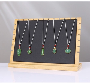 Detailed view of green faux jade pendants with silver woven cords on a bamboo wooden display