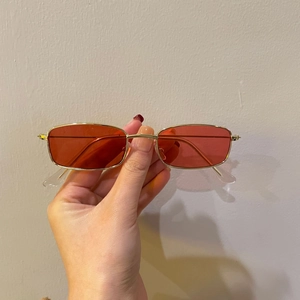 Detail of vintage gold metal frame sunglasses with translucent orange square lenses