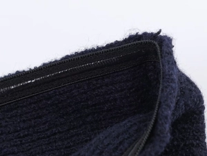 Close-up of the metal zipper detail on dark blue fuzzy knitted top with soft texture
