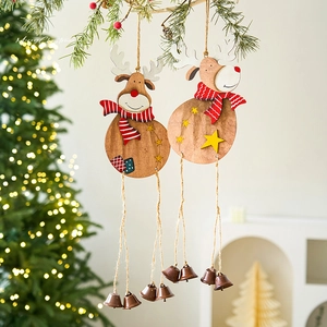 Wooden Christmas reindeer ornaments with bells and scarves hanging on an evergreen branch