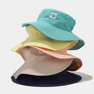 Vertical stack of kids sun hats in five pastel colors with smiley face patch detail