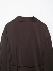 Detail view of the brown satin shirt collar and dropped shoulder seam on white background